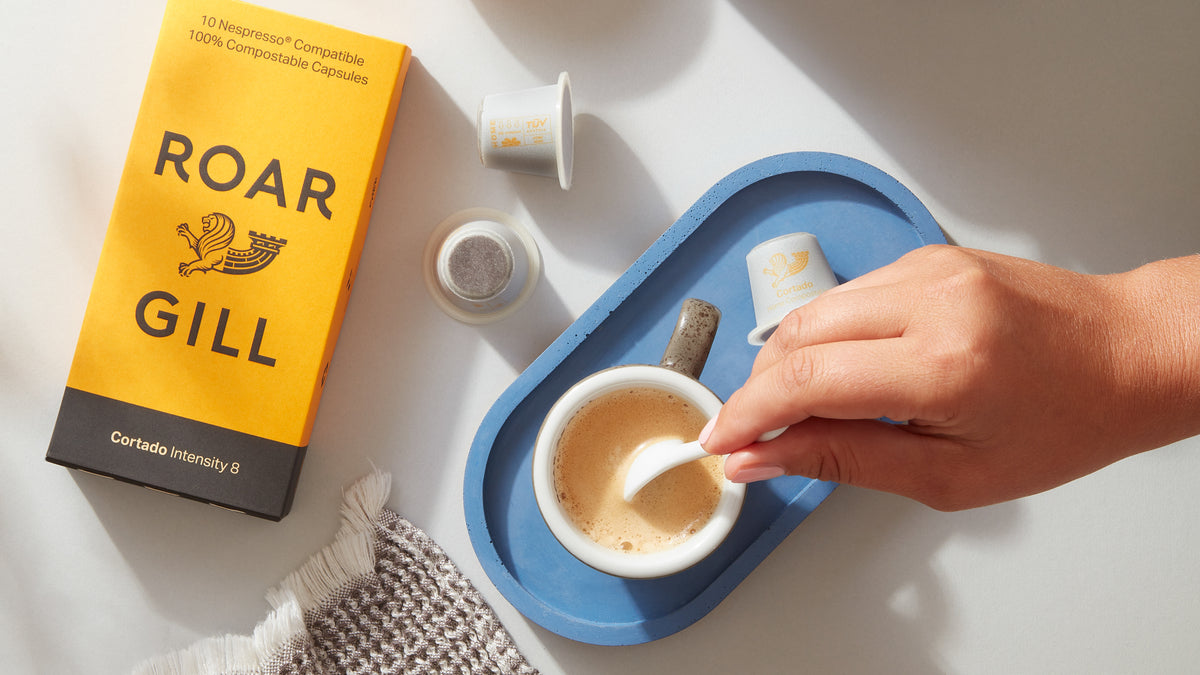 Cortado coffee pods, next to poured cortado being stirred.